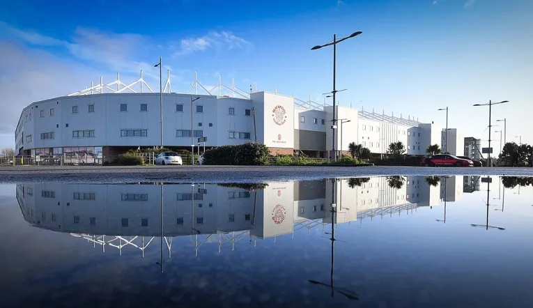Góc nhìn bên ngoài sân vận động Bloomfield Road, cho thấy quy mô và thiết kế tổng thể của sân nhà Blackpool FC, nổi bật giữa khu dân cư.