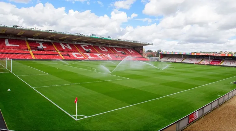 Góc nhìn từ khán đài xuống mặt sân cỏ xanh mướt của Sincil Bank, sân nhà lịch sử của câu lạc bộ Lincoln City FC, sẵn sàng cho các trận đấu bóng đá Anh.