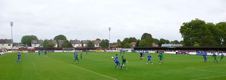Khung cảnh một trận đấu tại Kingsmeadow giữa AFC Wimbledon và Ramsgate, tái hiện một phần lịch sử sôi động của sân vận động này.