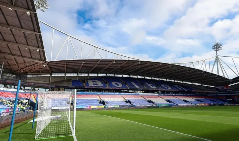 Toàn cảnh mặt sân Toughsheet Community Stadium từ phía khán đài, thể hiện chất lượng sân bãi