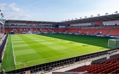 Toàn cảnh sân vận động Bloomfield Road, sân nhà của Blackpool FC, với các khán đài hiện đại và đường biên xanh mướt, thể hiện sự kết hợp giữa truyền thống và phát triển.